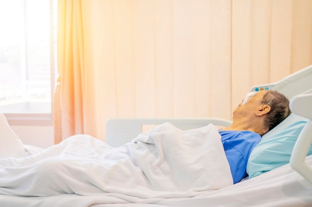 Recuperate after surgery treatment of postoperative cataract by the concept of caregiver an old asian man put a protective shield over her eyes to cover the cover to protect during nap time