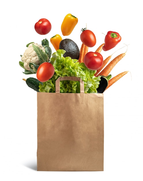 Photo recyclable paper bag with explosion of flying vegetables, concept healthy food and ecological recycling