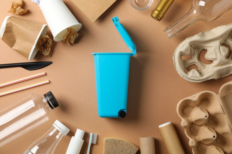 Photo recycle bin and different trash on craft background, top view