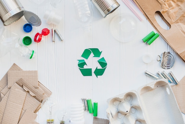 Photo recycle symbol with waste items on wooden white table