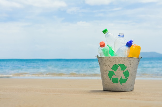 Recycleer, mand met plastic fles op het strand