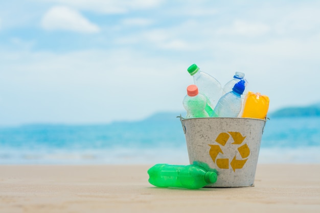 Recycleer, mand met plastic fles op het strand