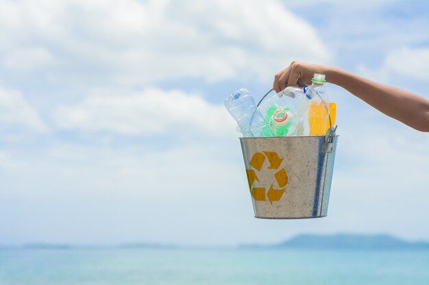 Recycleer, mand met plastic fles op het strand