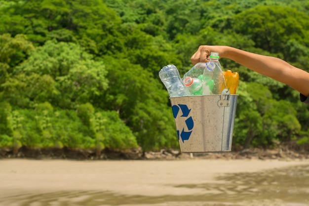 Recycleer, mand met plastic fles op het strand