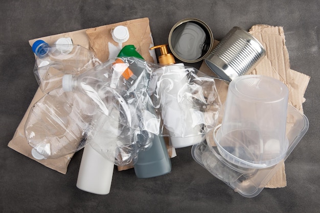 Concetto di riciclaggio ed ecologia smistamento dei rifiuti domestici plastica carta metallo catturato dall'alto disposizione piatta sfondo grigio in cemento