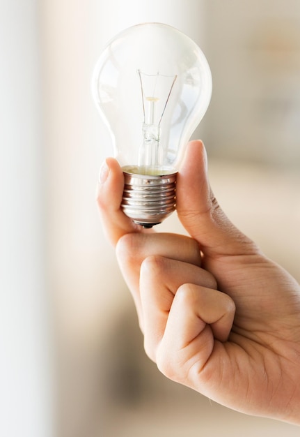 recycling, electricity, idea, environment and ecology concept - close up of hand holding lightbulb or incandescent lamp