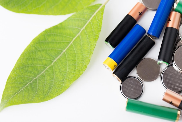 recycling, energie, kracht, milieu en ecologisch concept - close-up van groene alkalinebatterijen en blad