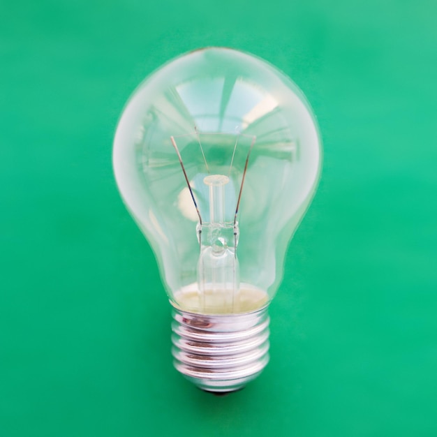 recycling, energy saving, electricity, environment and ecology concept - close up of lightbulb or incandescent lamp on green