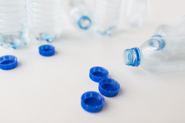 концепция переработки, здорового питания и хранения продуктов питания - крупный план пустых использованных пластиковых бутылок с водой и крышек на столе