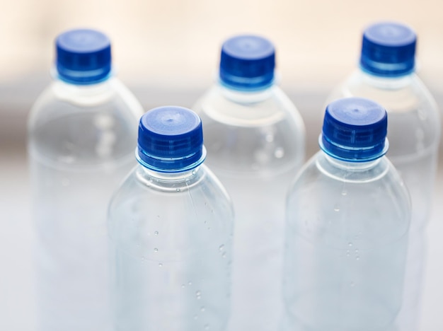 recycling, healthy eating and food storage concept - close up of plastic bottles with pure drinking water on table