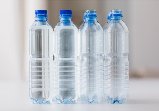 recycling, healthy eating and food storage concept - close up of plastic bottles with pure drinking water on table