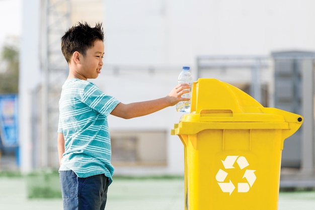 In the recycling point bin one boy puts plastic water bottle