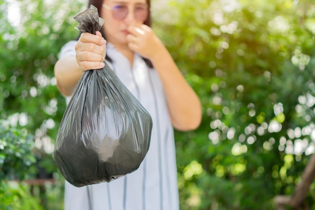 Recycling, sortering en duurzaamheid concept jonge Aziatische vrouw met stinkende plastic zak voor vuilnis