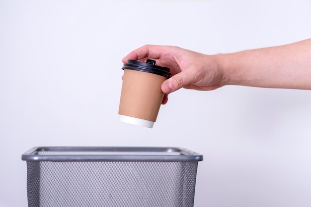 Recyclingaparte afvalinzameling hand gooit een kopje koffie in de prullenbak