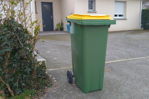 Foto recyclingbak groene vuilnisbak met geel deksel voor het sorteren van recycleerbare verpakkingen voor het huis