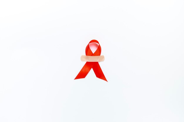 Red AIDS awareness ribbon on white background. Close up copy space.