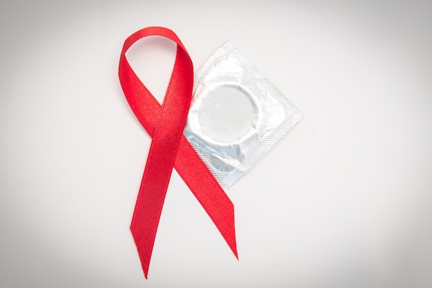 red aids ribbon beside condom