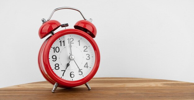 Red alarm clock on grey wall background