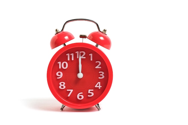 Photo red alarm clock is isolated on a white background, shows twelve clock, night and lunch time.