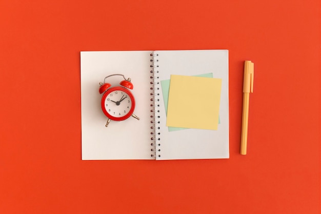 Red alarm clock and notebooks with space for text on red background