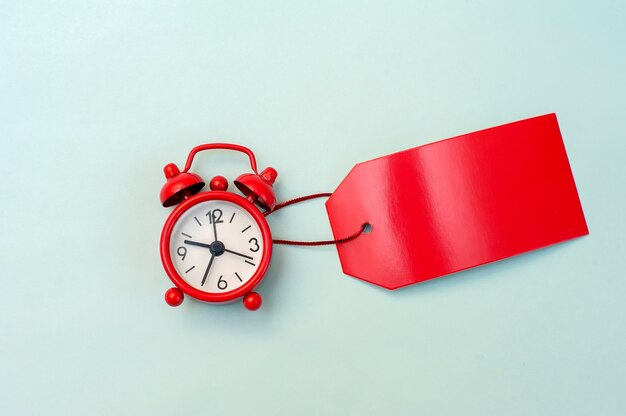 Red alarm clock and red label blank for an inscription on a blue background