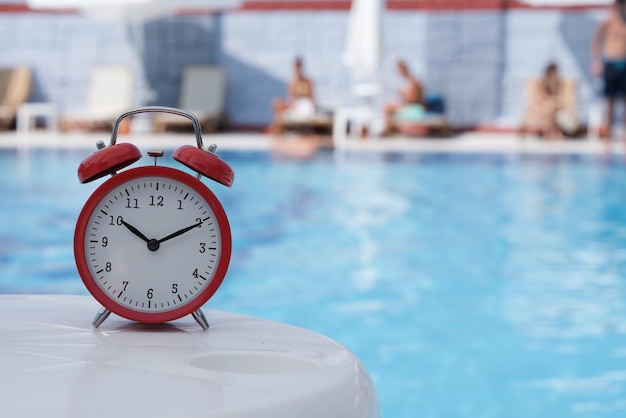 Red alarm clock for ten oclock near pool in hotel or spa center