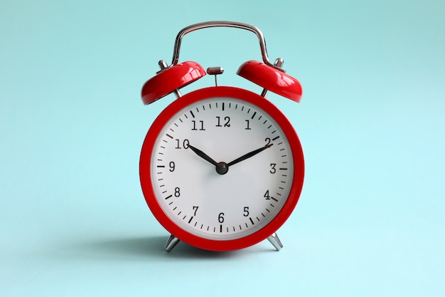 Red alarm clock on turquoise background shows