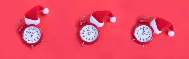 Red alarm clock with Christmas Santa hat on the red background Christmas banner Copy space