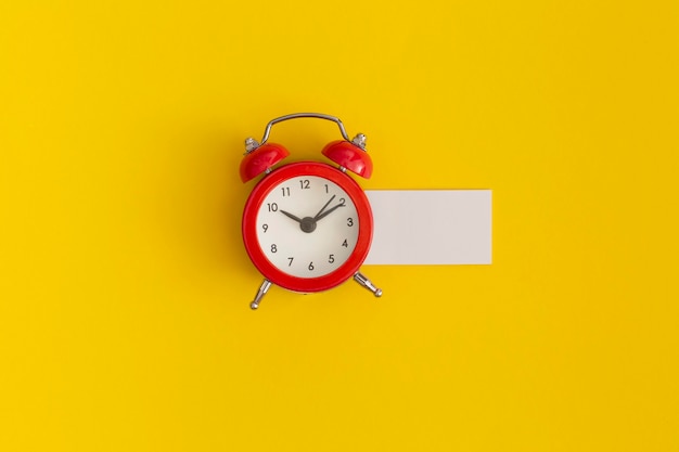 Red alarm clock on yellow background