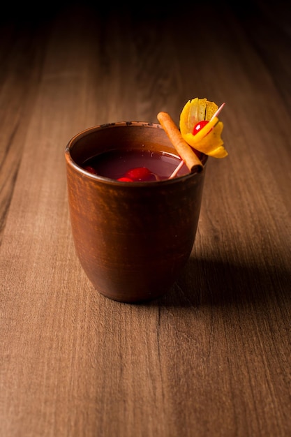 Red alcoholic cocktail in a clay glass closeup on a wooden bar\
counter