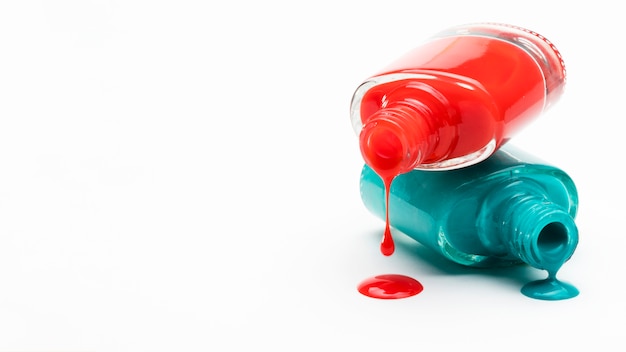 Красный и зеленый лак для ногтей пролился из бутылки с белой копией пространства фоне