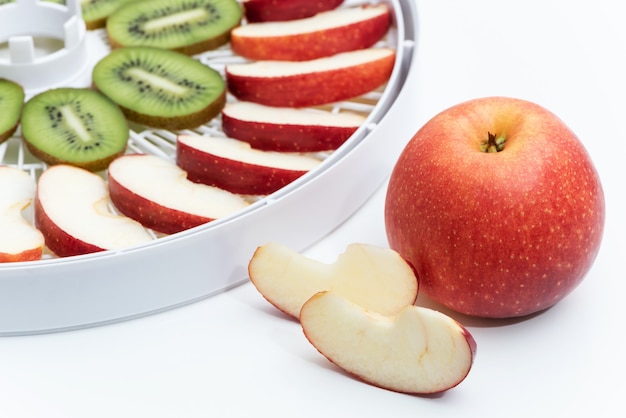 Red apple on the background of a dehydrator tray with apples slices.