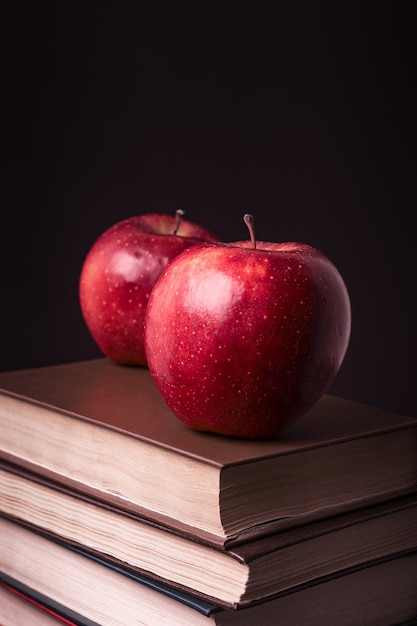 Red apple on book stack on black background