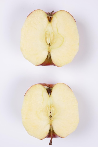 Red apple cut in half isolated on white background Sliced apple with a tail closeup Two halves of an bio healthy apple View from above