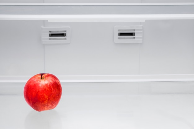 Red apple in a empty refrigerator.