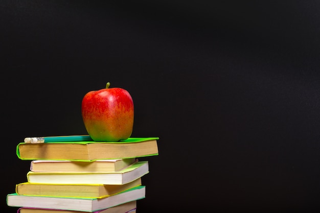 Red apple and old books on wooden tabletop