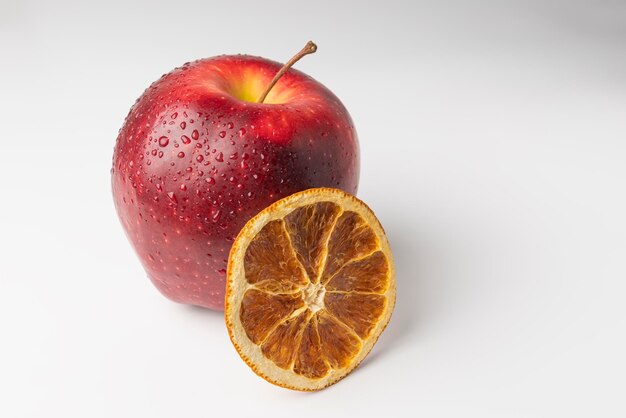 Red apple and a slice of dried orange on a white background