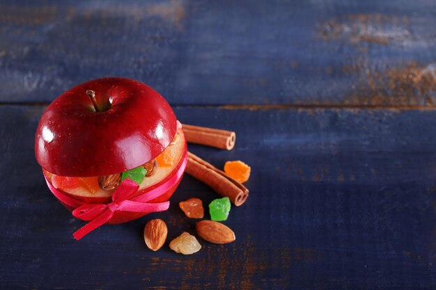 Red apple stuffed with dried fruits with cinnamon and almond on color wooden background