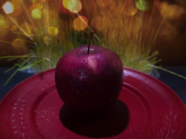 Red apple on a stylish red plate on a dark background