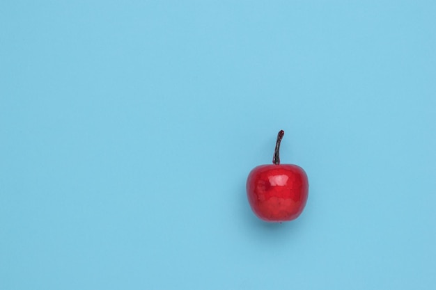 Red apple in syrup on a blue background. Minimalism. The concept of a winter sweet apple dish. Flat lay.