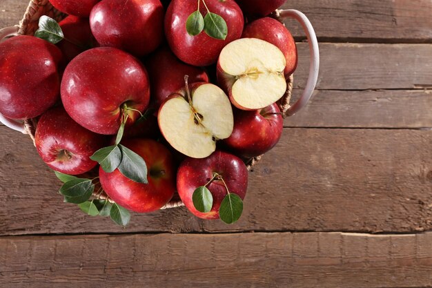 Red apple in wicker basket on wooden table top view