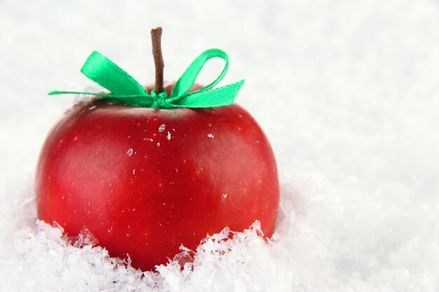 Red apple with bow in snow close up