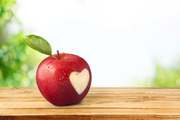 Красное яблоко с вырезом в форме сердца. на заднем плане