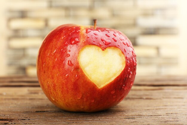 Red apple with heart on wooden table, close-up