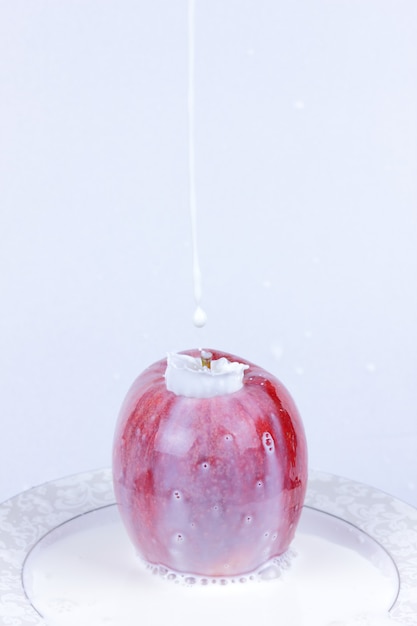 Red apple with pouring milk. Apple with milk splash