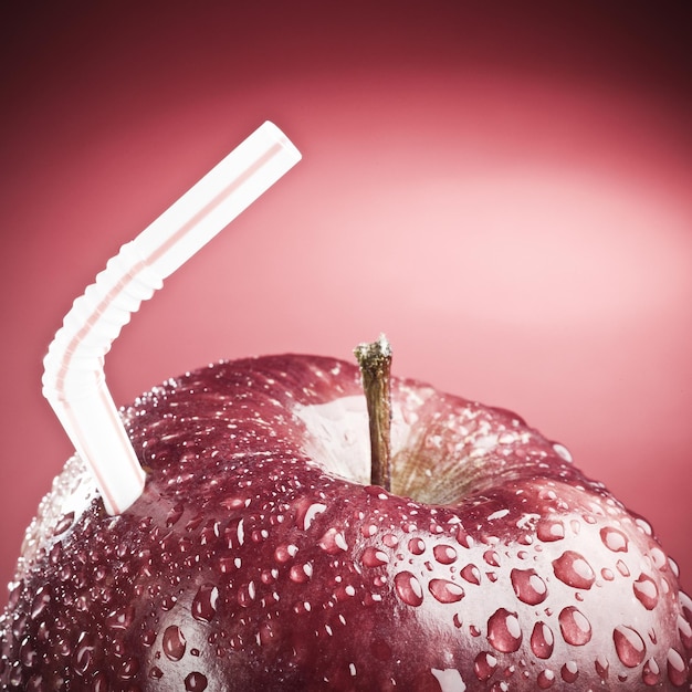 Photo a red apple with a white straw and a straw that says 