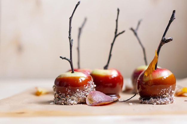 Red apples in caramel, sprinkled with nuts, on a light plywood background