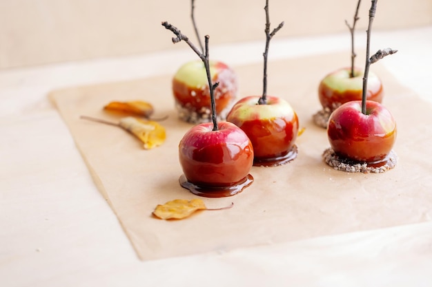 Red apples in caramel, sprinkled with nuts, on a light plywood background