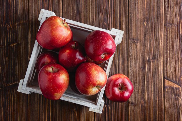 Red apples in a crate on a wooden background