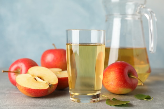 Red apples and glasses with juice on grey table